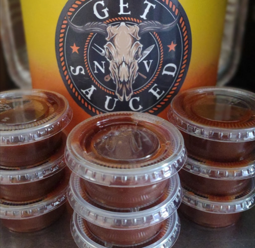 A stack of clear containers filled with sauce, with a colorful "Get Sauced" logo in the background.