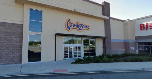 Exterior of a building featuring the "ClimbZone" sign, with large glass doors and a landscaped entrance.