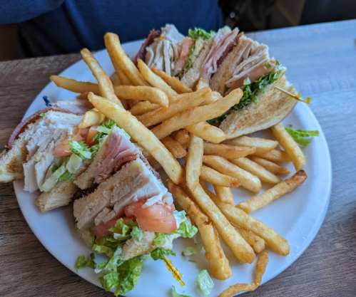 A plate with a sandwich filled with turkey, lettuce, and tomato, accompanied by a side of golden French fries.