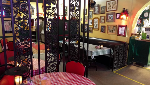 Cozy restaurant interior with checkered tablecloths, decorative walls, and dim lighting, featuring intimate seating areas.