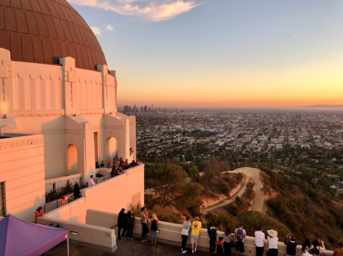 View of the Griffith Observatory at sunset, overlooking the city of Los Angeles and surrounding hills.