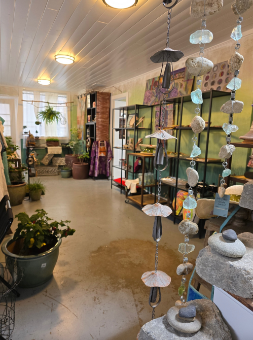 A cozy shop interior with plants, shelves of items, and decorative hanging ornaments. Soft lighting enhances the atmosphere.