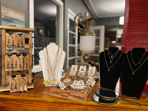 A display of various jewelry pieces, including earrings, necklaces, and decorative stands, in a cozy shop setting.