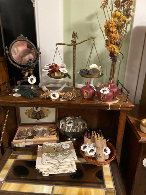 A vintage display featuring scales, pomegranates, dried flowers, and various decorative items on a wooden table.