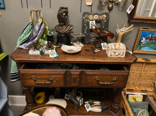 A vintage wooden table displays various decorative items, including a bust, shells, and unique trinkets.