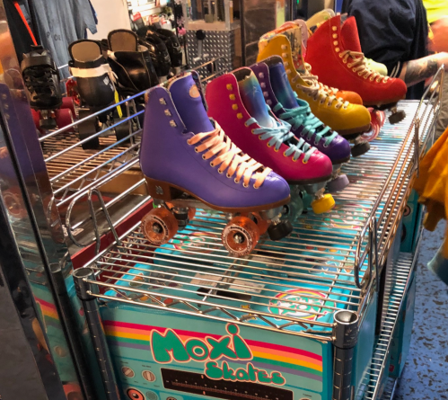 A display of colorful roller skates on a metal rack, featuring various vibrant styles and sizes.