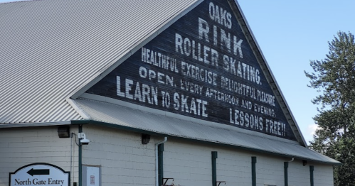 A large building with a sign promoting roller skating, lessons, and various activities at Oaks Rink.