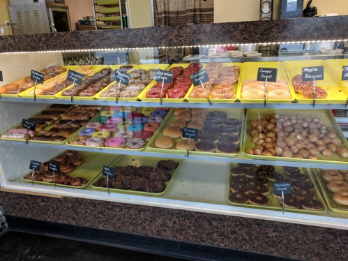A display case filled with various donuts, including glazed, frosted, and specialty flavors.