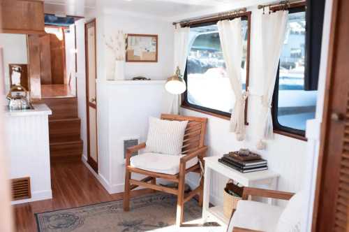 Cozy interior of a boat with wooden furniture, large windows, and warm lighting, creating a welcoming atmosphere.