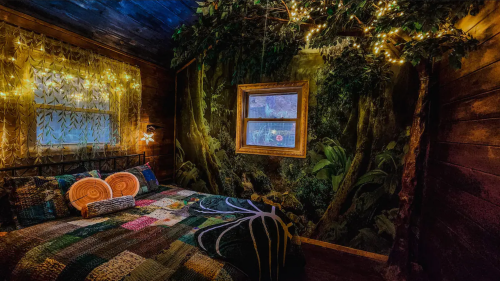 Cozy bedroom with a nature-themed mural, fairy lights, and a patchwork quilt on the bed.