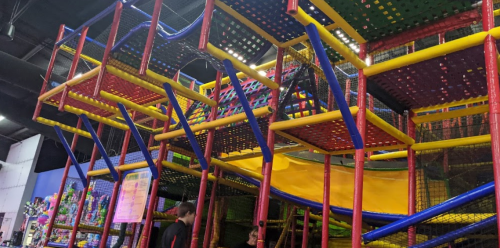 Colorful indoor play structure with multiple levels, slides, and climbing areas for children.