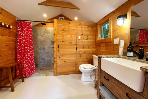 Cozy bathroom with wooden walls, a shower with a floral curtain, and modern fixtures. Bright and inviting space.