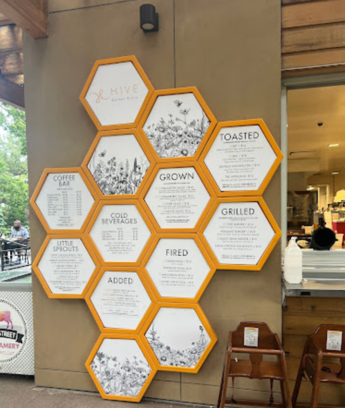 Menu display featuring hexagonal panels with food and drink options at Hive Natural Eats.