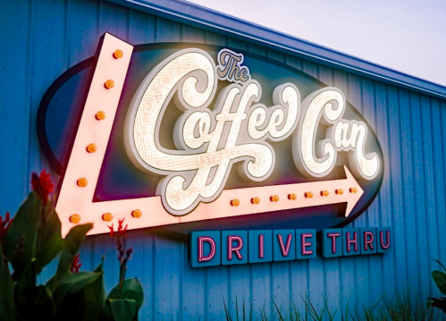 Brightly lit sign for "The Coffee Can Drive Thru" with decorative lights and an arrow design.
