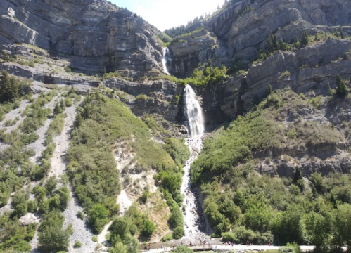 A stunning waterfall cascading down a rocky mountain, surrounded by lush greenery and a rocky landscape.