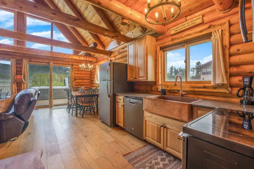 Cozy log cabin kitchen with wooden cabinets, stainless appliances, and a dining area with mountain views.