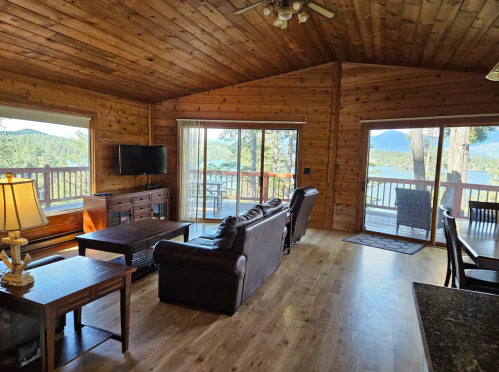 Cozy wooden cabin interior with a living area, large windows, and a view of the outdoors.
