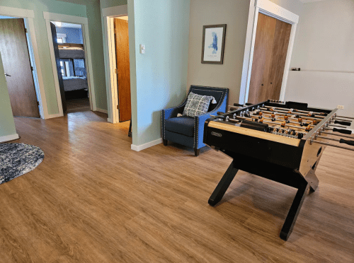 A cozy room featuring a foosball table, a blue armchair, and doorways leading to other rooms.