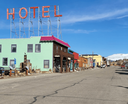 A colorful street scene featuring a vintage hotel sign and various buildings under a clear blue sky.