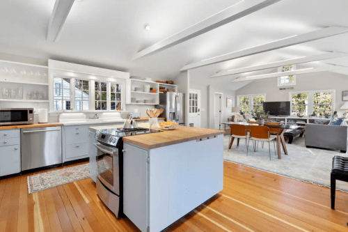 Bright, modern kitchen with a central island, stainless steel appliances, and an open layout to a cozy living area.