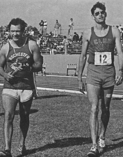 Two male athletes walking on a track field, one in a "Rochester Track Club" shirt and the other in a "Club Wes" shirt.
