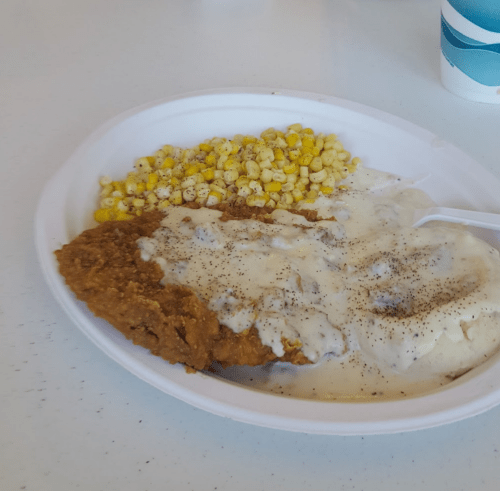 A plate of fried chicken with gravy, mashed potatoes, and a side of corn.