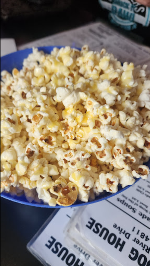 A blue bowl filled with freshly popped popcorn, with some kernels slightly browned.