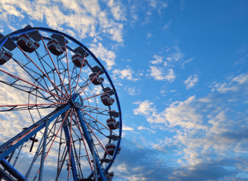 A colorful ferris wheel against a blue sky with scattered clouds.