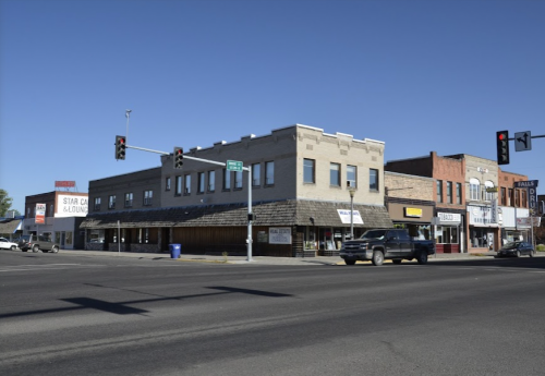 A street view of a small town with brick buildings, traffic lights, and a clear blue sky.