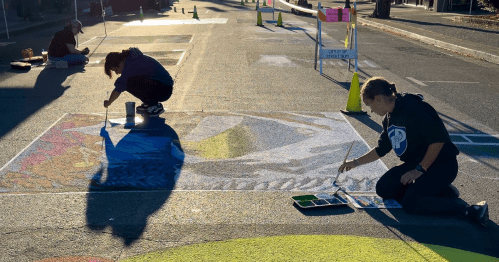 Artists create street art during at sunset during an Oregon festival.