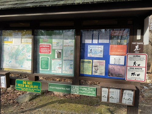 Information kiosk displaying maps, park rules, and guidelines for visitors, including dog leash and waste policies.