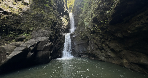 A serene waterfall cascading into a tranquil pool, surrounded by lush, rocky cliffs.