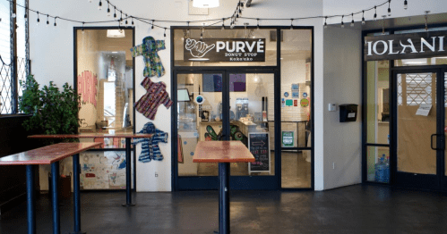 Entrance to Purvé, a café with a modern design, featuring outdoor seating and colorful decor.