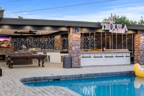 Outdoor bar area with swings, pool, and a sign reading "Tequila," surrounded by stone walls and modern decor.