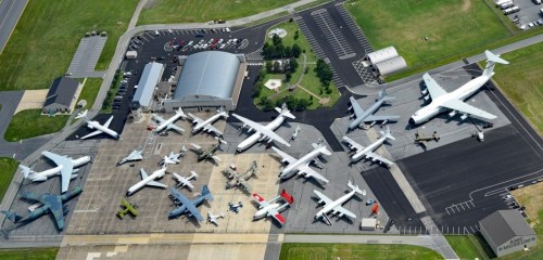 Aerial view of a large aircraft display featuring various planes parked on a tarmac with surrounding facilities.