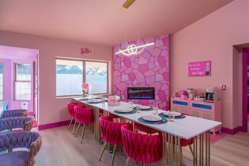 pink barbie dreamhouse with a dining table, pink chairs, and pink rock-like fireplace