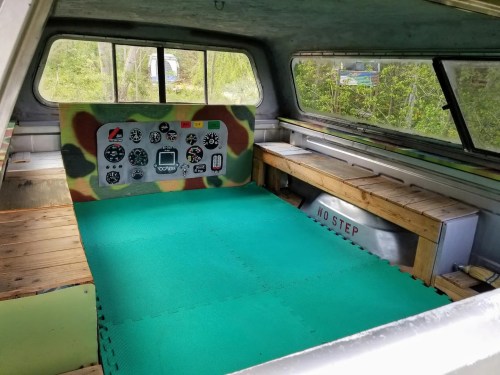 Interior of a vehicle with a green floor mat, wooden benches, and a dashboard featuring various gauges and controls.
