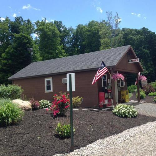 A small brown office building surrounded by greenery and flowers, with an American flag displayed outside.