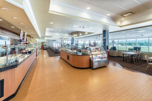 A spacious buffet restaurant with a variety of food stations and large windows overlooking a scenic view.