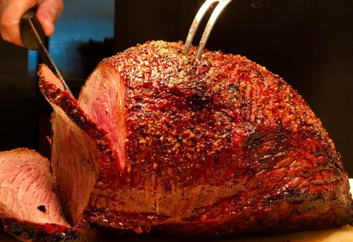 A perfectly cooked roast with a crispy crust, being sliced with a fork in a warm, inviting setting.