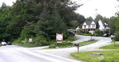 A gravel road leads to a house surrounded by trees, with a sign reading "Over Wonder" and parked cars nearby.