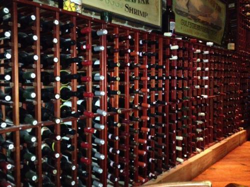 A wooden wine rack filled with various bottles of wine in a dimly lit setting.