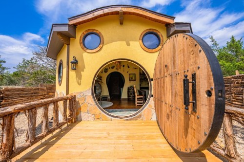 outdoor exterior of hobbit house with a circular doorway and circular windows above