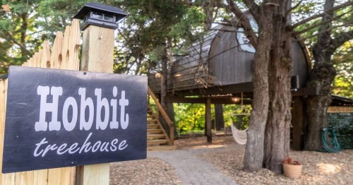 outdoor photo of home with a sign that says "Hobbit Treehouse"