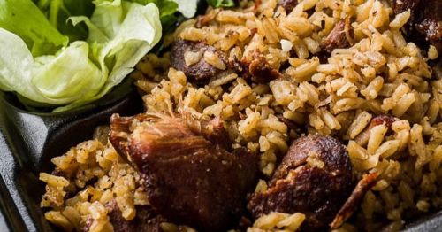 A close-up of a dish featuring seasoned rice and tender meat, accompanied by fresh lettuce leaves.