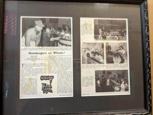 Framed newspaper clippings featuring an article about "Hamburgers on Wheels" and photos of a diner scene from 1952.