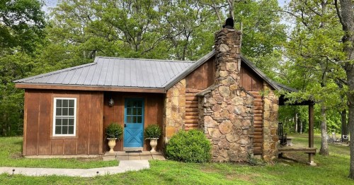 a wooden and stone cabin with a bright blue front door
