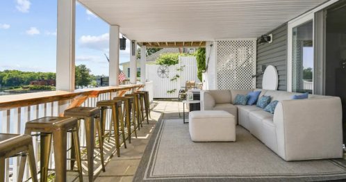 high chairs overlooking the lake on the outdoor patio with a white couch nearby