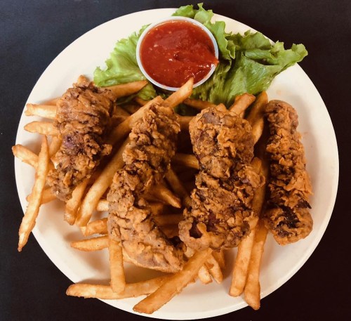 A plate of crispy fried chicken tenders served with French fries and a side of dipping sauce on lettuce.
