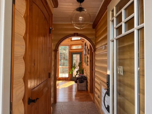 A cozy wooden hallway with an arched entrance, featuring natural light and a warm, inviting atmosphere.